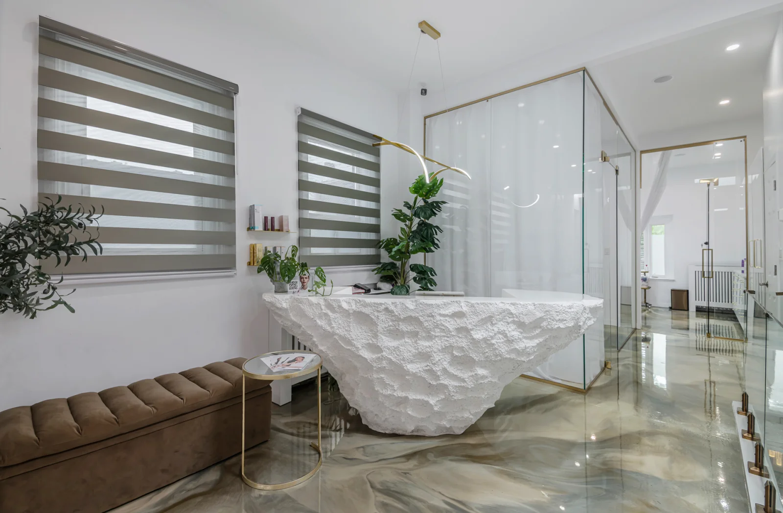 Activate Beauty reception — sculptural stone desk, glass treatment room and marble floor, Miami